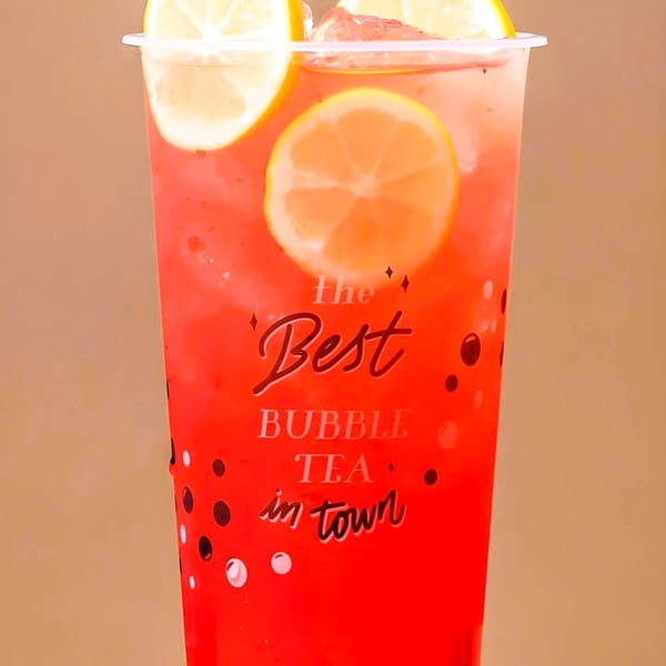 A vibrant red bubble tea with lemon slices and ice, in a clear cup with "The Best Bubble Tea in Town" text.