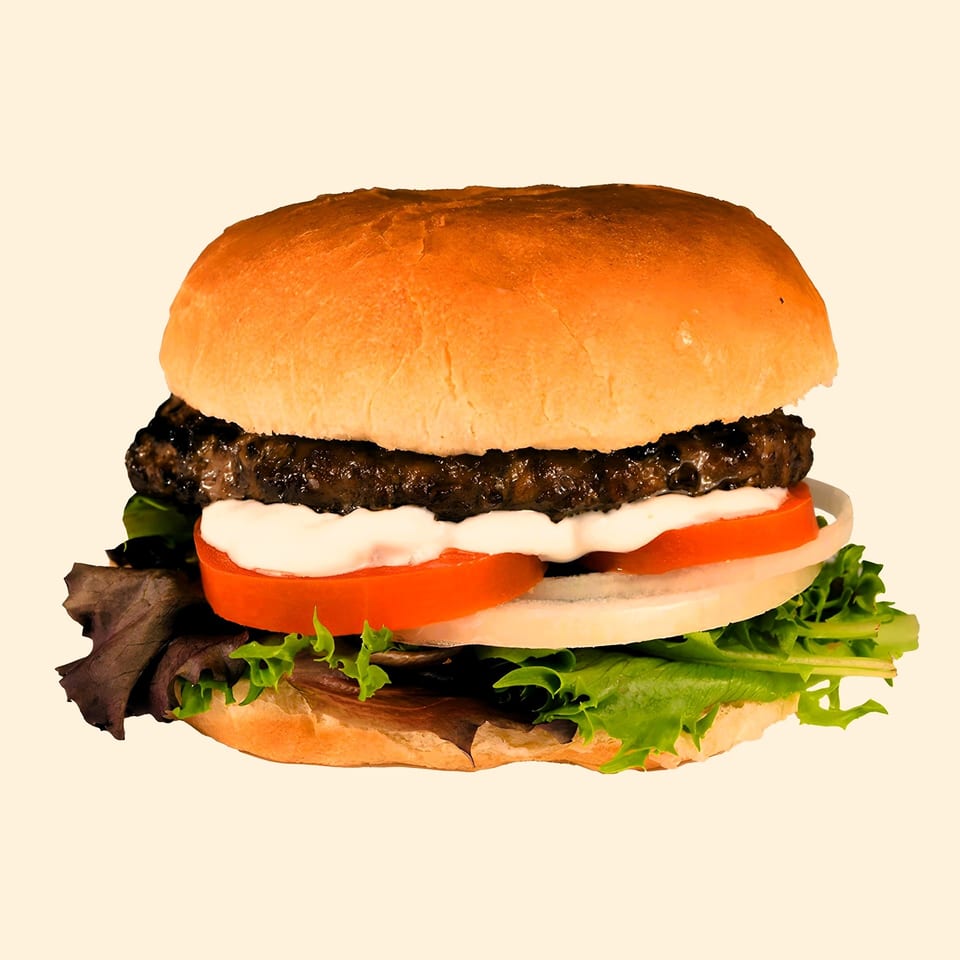 M2 Burger with a beef patty, lettuce, tomato, onion, and white sauce on a bun.