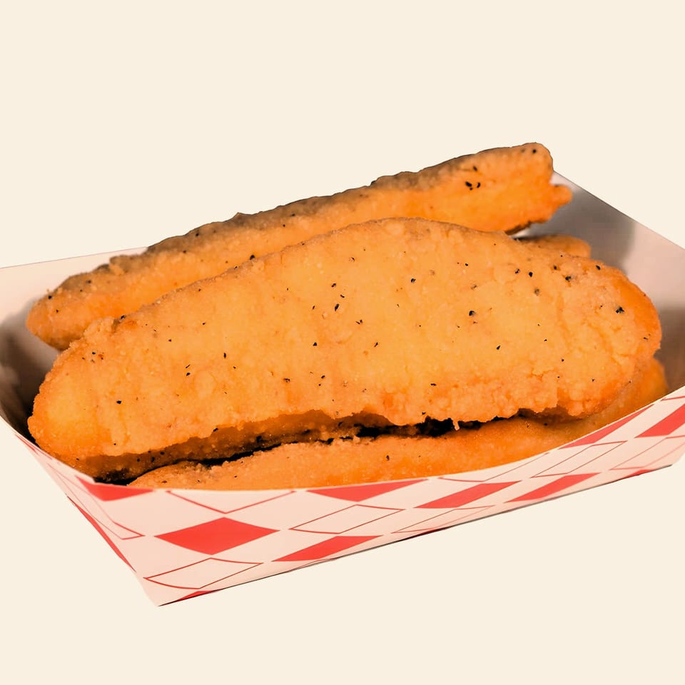 Three golden-brown fried fish fillets, seasoned with pepper, in a red and white checkered paper tray.